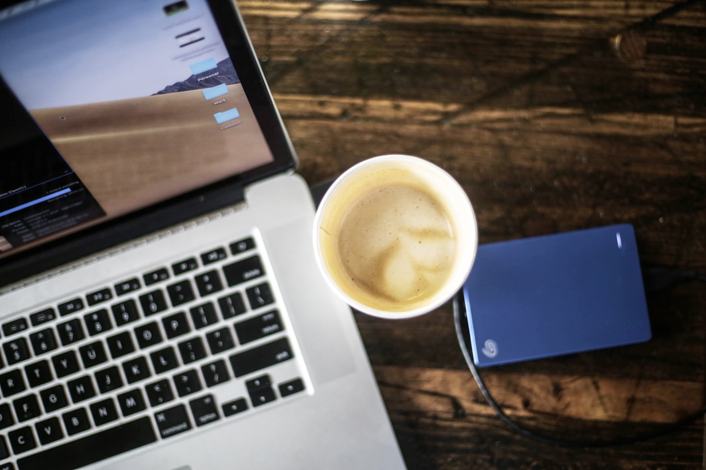 Laptop with work folders and latte art on desk.